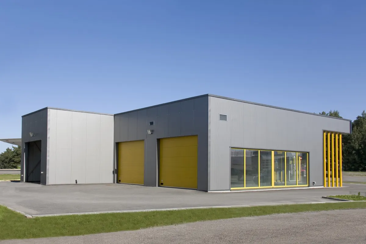 Commercial building with gray metal wall panels, yellow overhead doors and a glass storefront