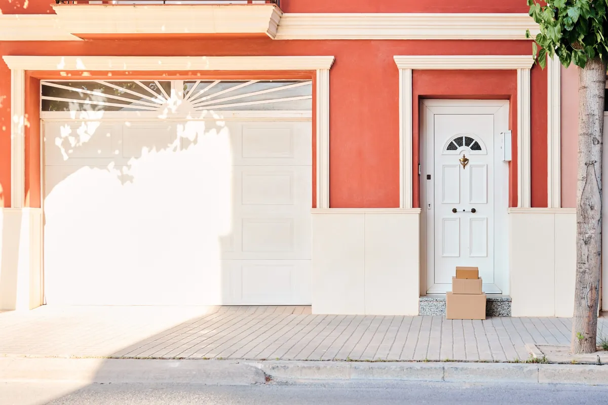 Coral stucco house front with white trim, a white garage door and a white front door