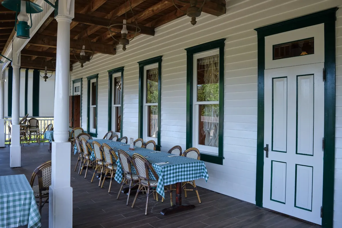 Restaurant porch with white lap siding, dark green window and door trim and white columns