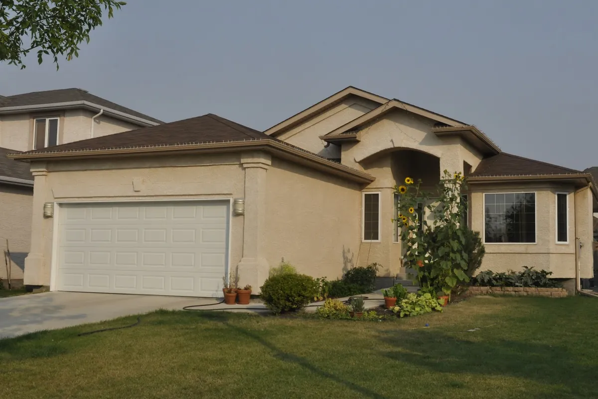 Single storey tan stucco home with a white garage door