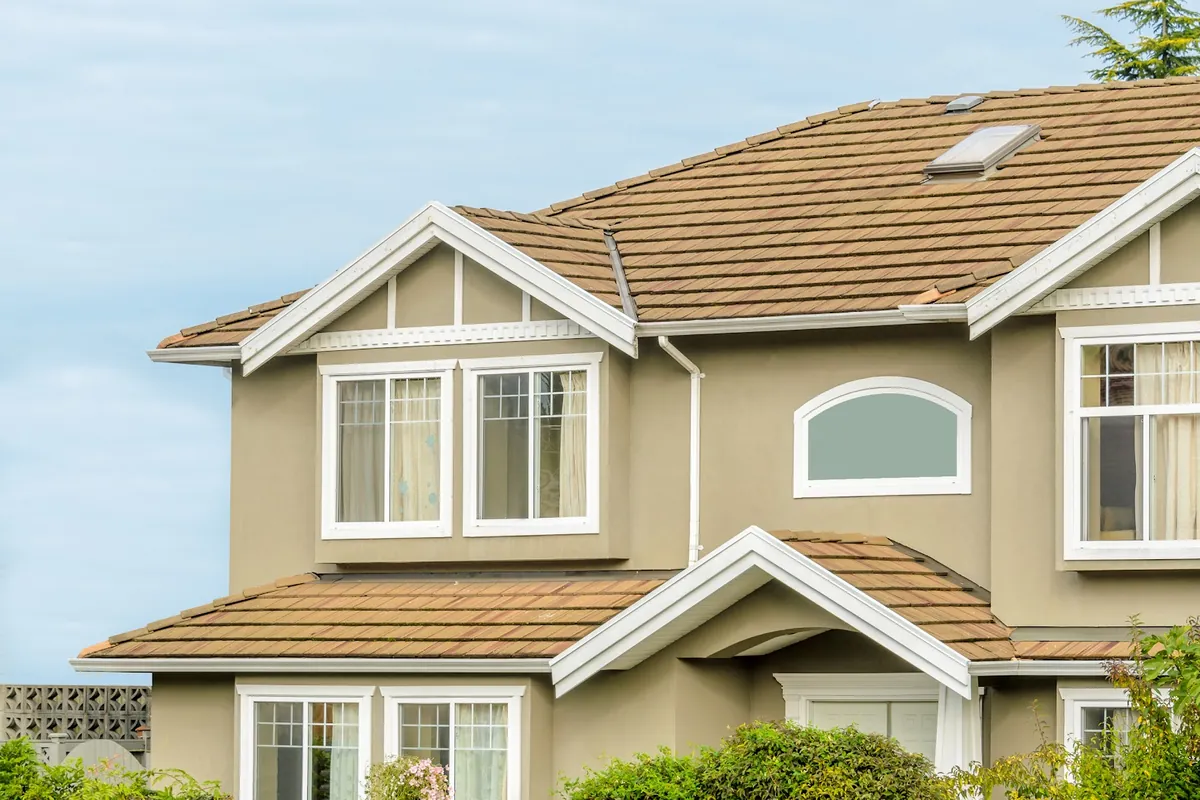 Two storey stucco home with white trim and a tile roof
